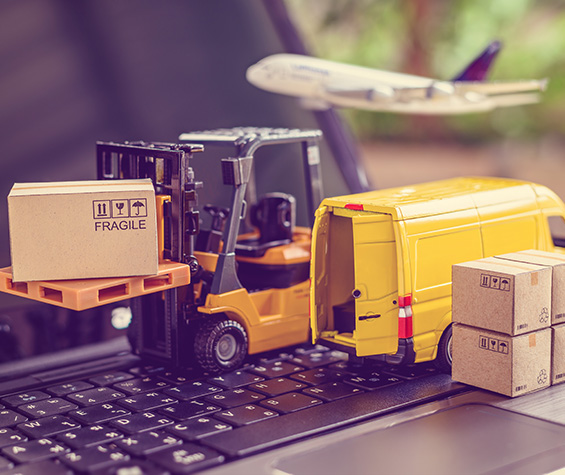 Gabelstapler, Transporter & Verpackungen als Miniaturen auf einer Tastatur mit Flugzeug im Hintergrund
